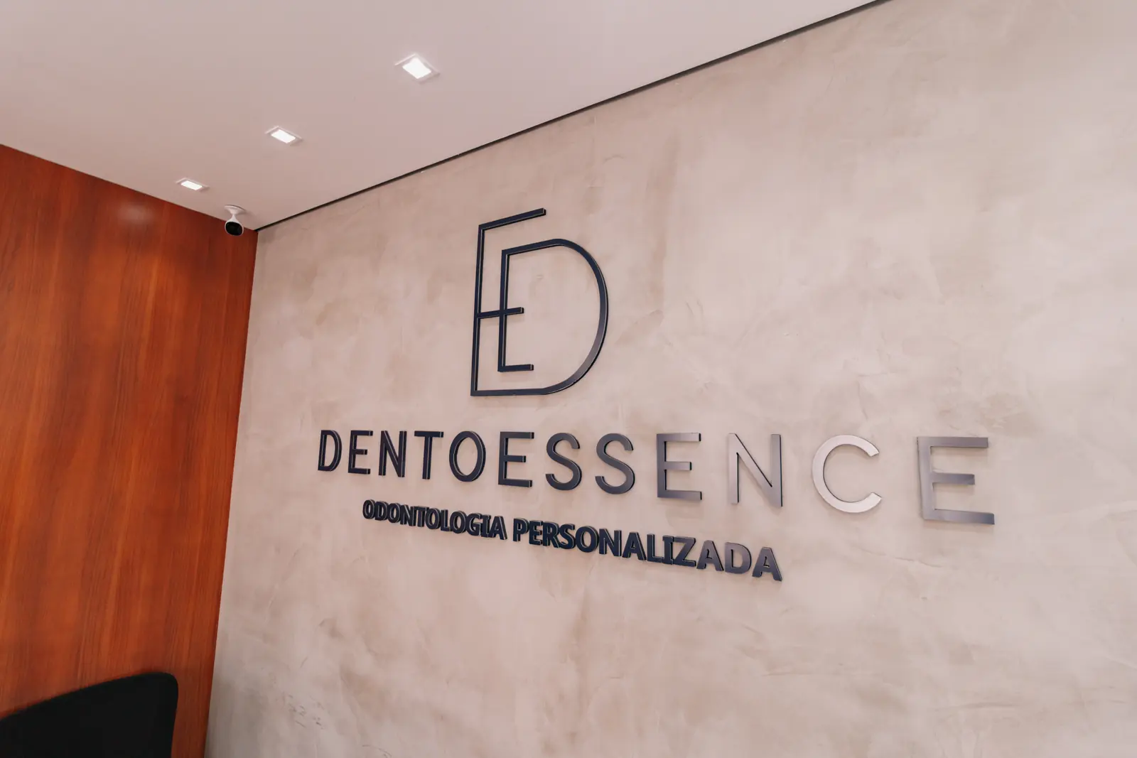 Marca DentoEssence aplicada na parede de cimento queimado da recepção